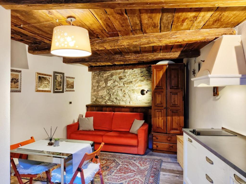 a living room with a red couch and a table at Piccolo Rifugio - Alpine Studio flat Valtournenche in Valtournenche