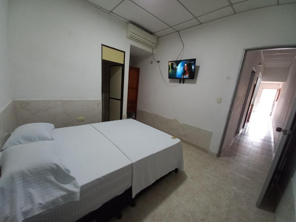 a bedroom with a white bed and a tv on the wall at Apartamento Jarhel in Aguachica