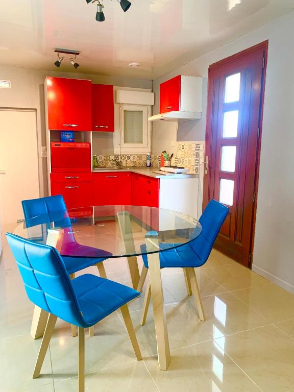 une cuisine avec une table en verre et des chaises bleues dans l'établissement Maison entière entre Orléans et Montargis, à Chailly-en-Gâtinais