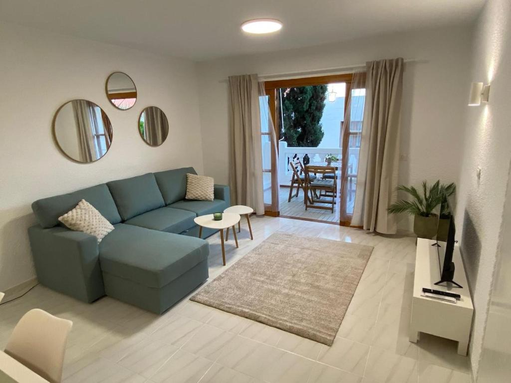 アロナにあるApartment Jasmine Los Cristianos, heated poolの青いソファとテーブルのあるリビングルーム