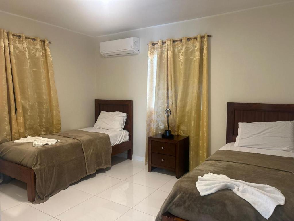 a bedroom with two beds and a window with curtains at Los Magicos Apartments, Bonaire in Kralendijk