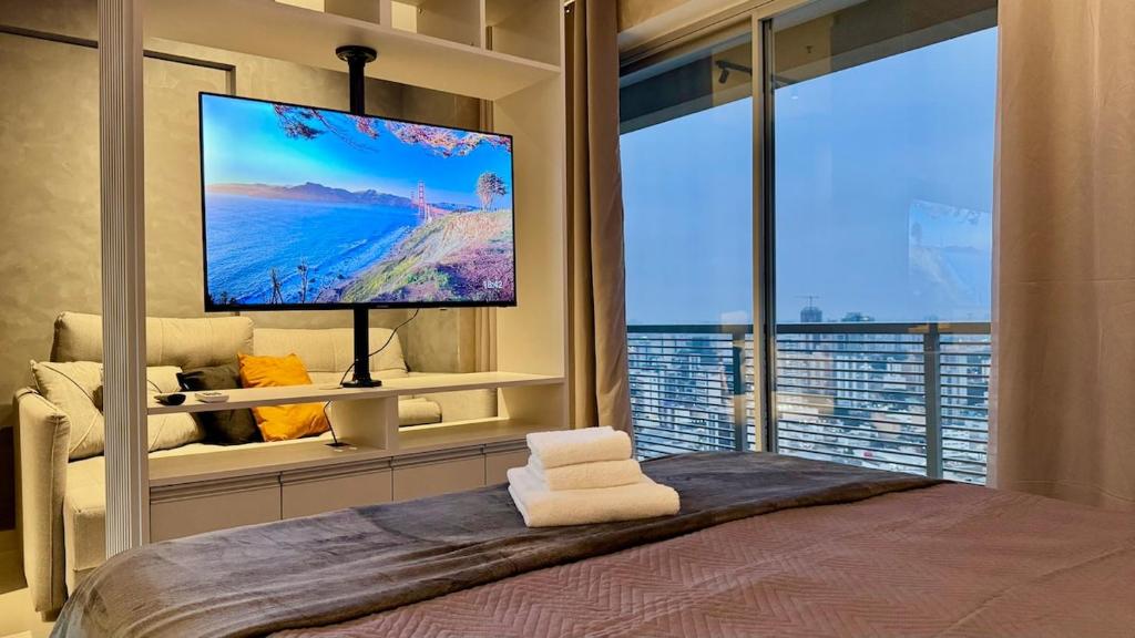 a bedroom with a large screen tv and a bed at The CityPlex | Apartamentos Prime no Centro de Osasco in Osasco