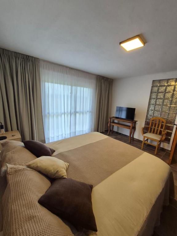 a bedroom with two beds and a chair and a window at Mirada al Champaqui - Departamento de Montaña in Villa Yacanto
