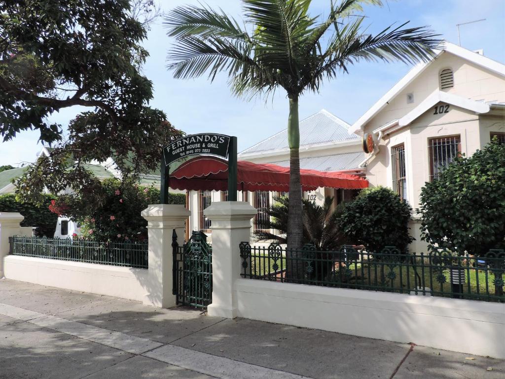 une maison avec un portail et un palmier dans l'établissement Fernando's Guest House, à Port Elizabeth