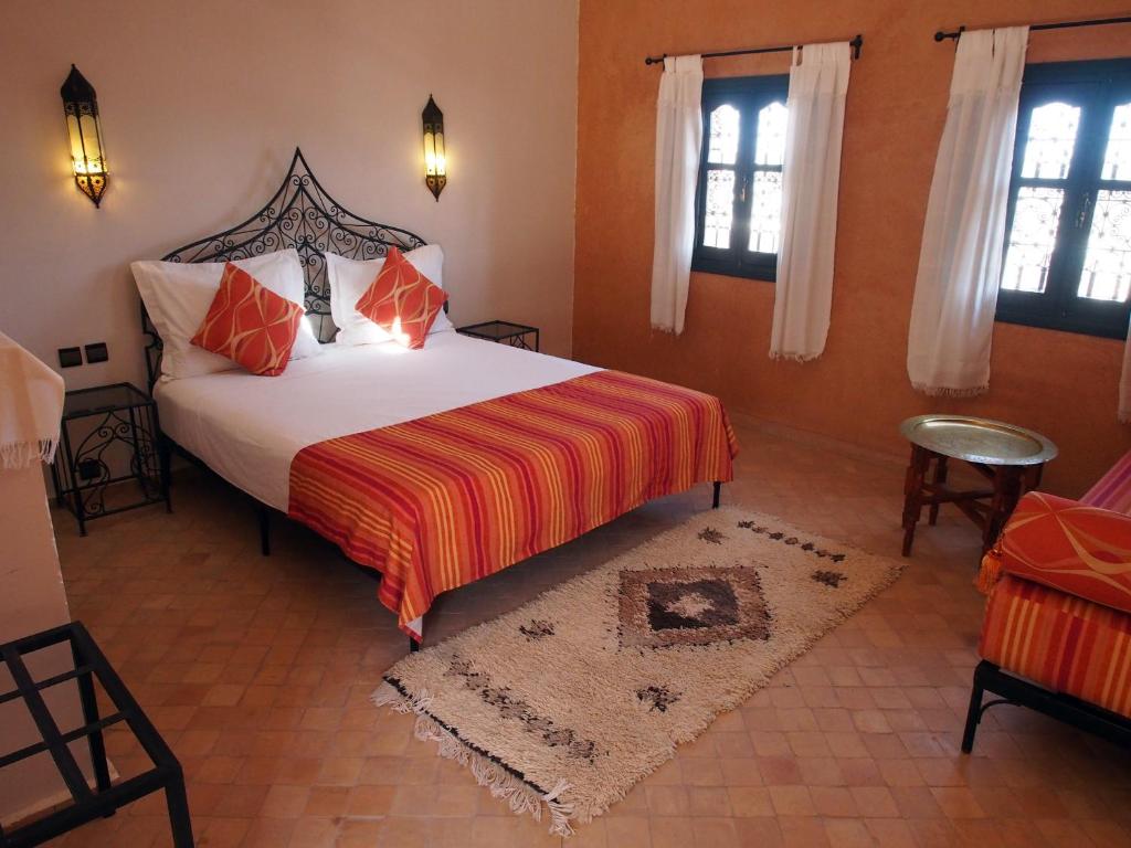a bedroom with a large bed with orange walls and windows at Riad Bouchedor in Ouarzazate