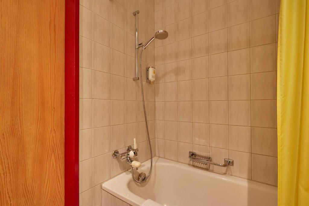 a bathroom with a bath tub with a shower at Hotel Sonnwendhof Engelberg in Engelberg