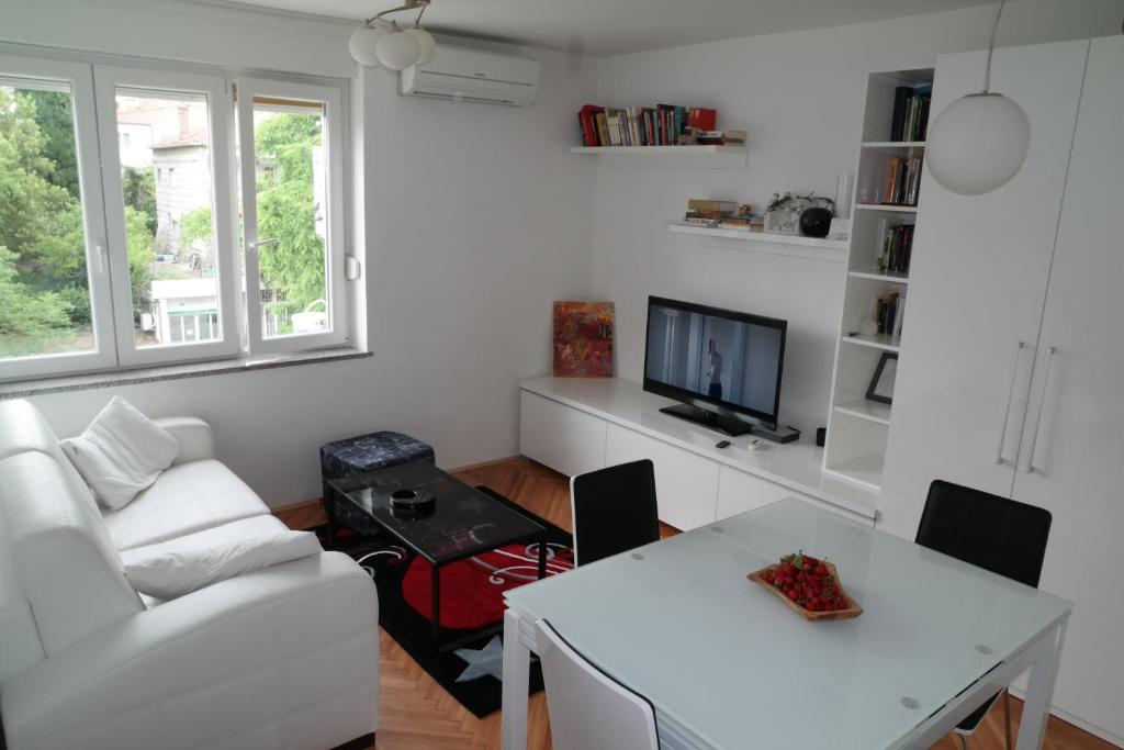 een woonkamer met een witte bank en een tafel bij Apartment Penny in Split
