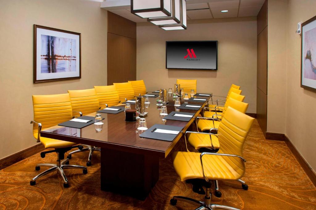 a conference room with a long table and yellow chairs at Newark Liberty International Airport Marriott in Newark
