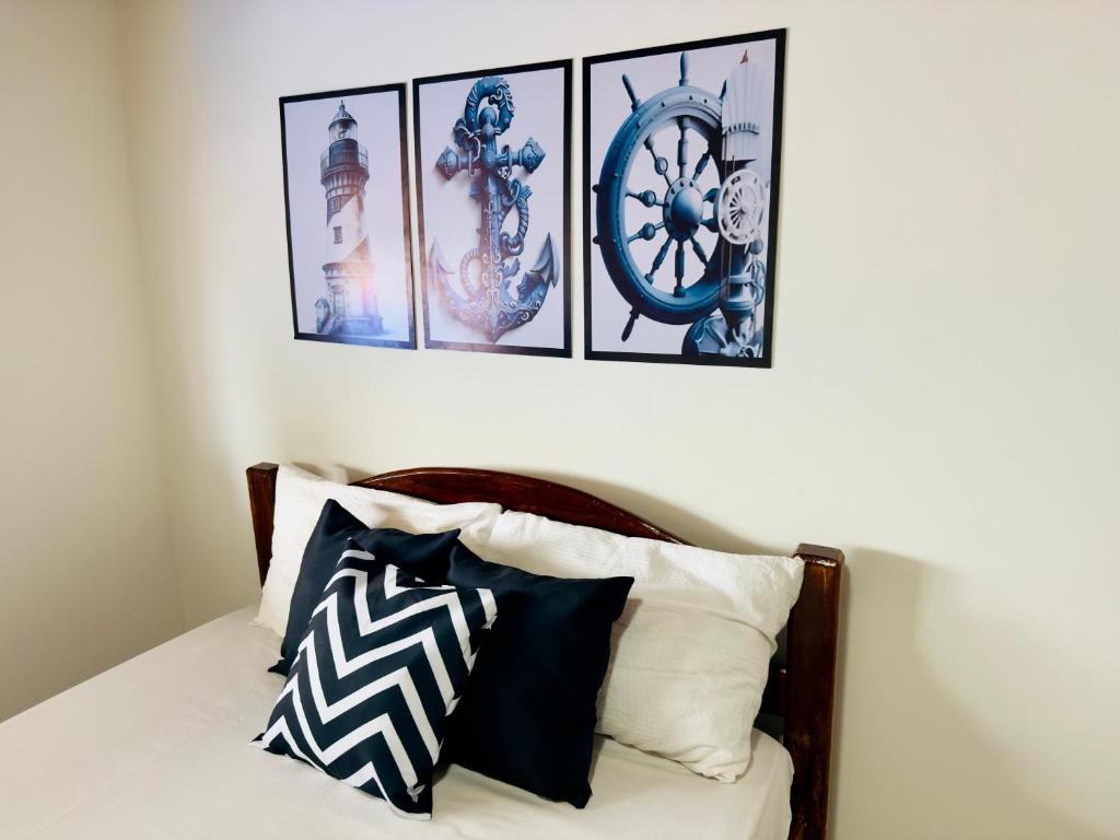 a bedroom with a bed with four pictures on the wall at Guest House Rosa do Mar in Olinda