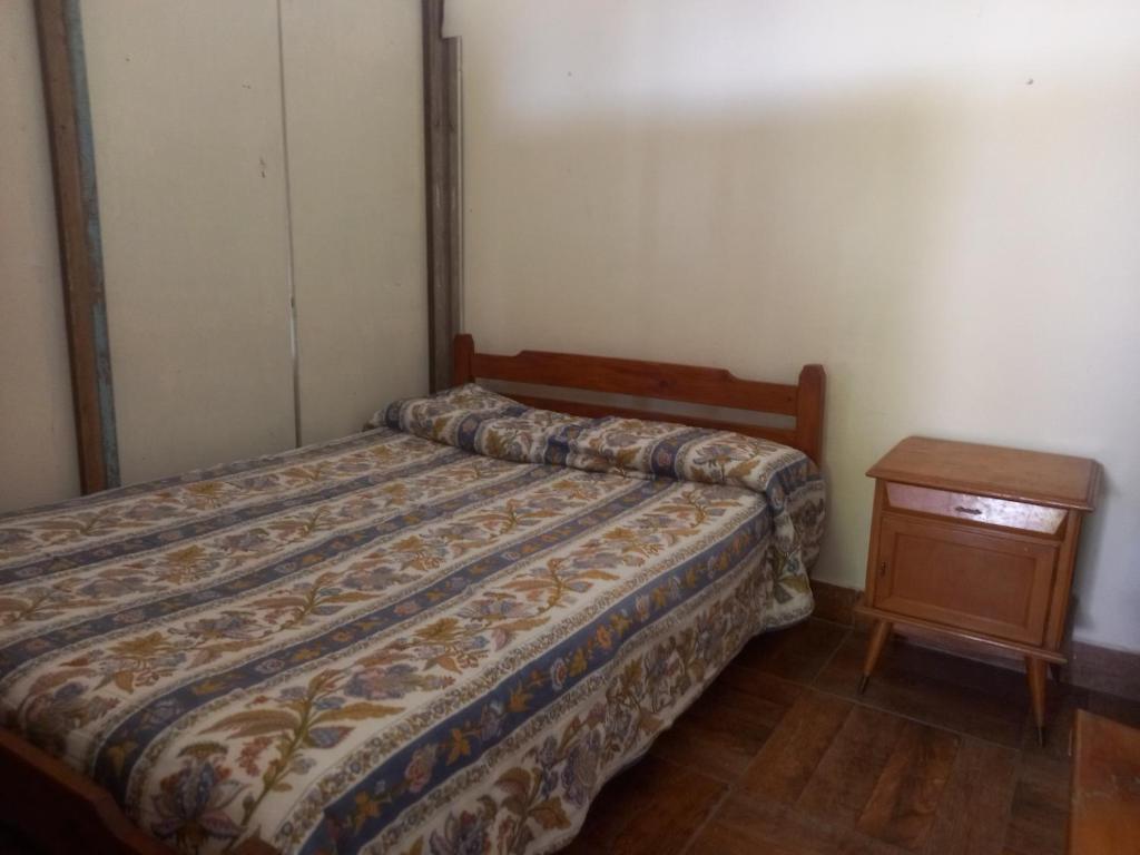 Un dormitorio pequeño con una cama y una mesita de noche. en El jardín, en General Juan Madariaga