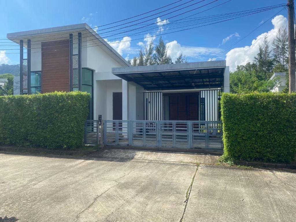 a white house with a gate and some bushes at Phuket Mali house in Ban Sam Kong