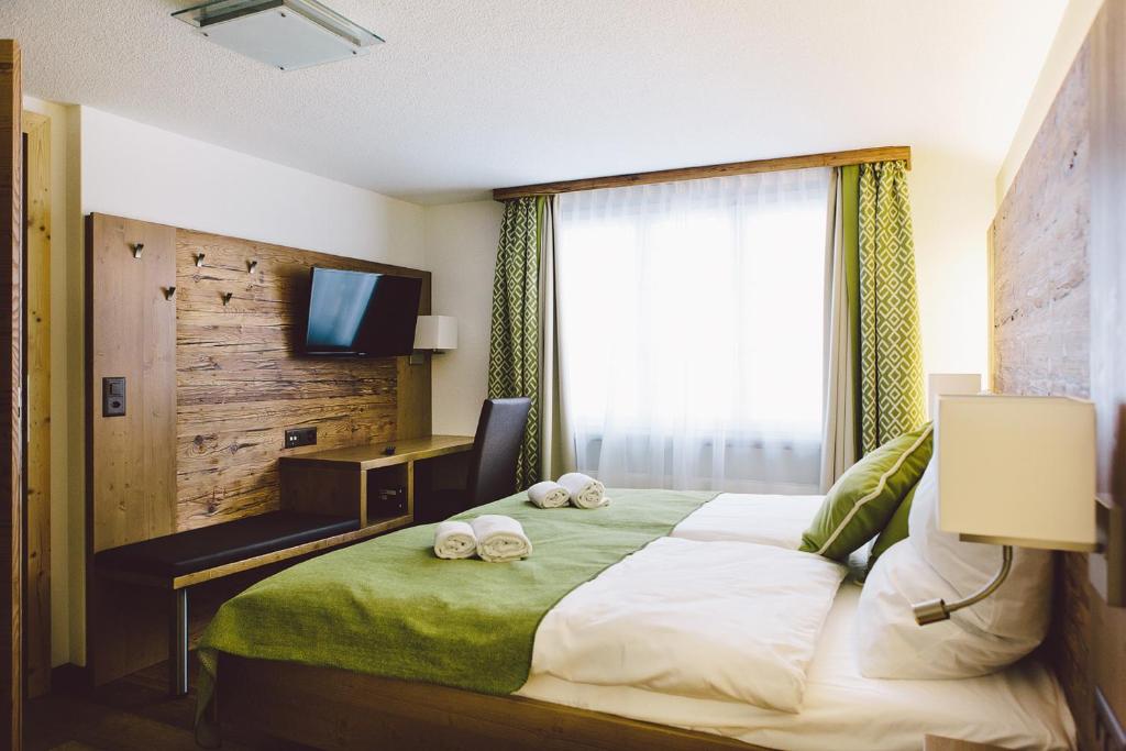a bedroom with a bed with a television and two slippers at Hotel & Restaurant Zum Schwarzen Bären in Andermatt