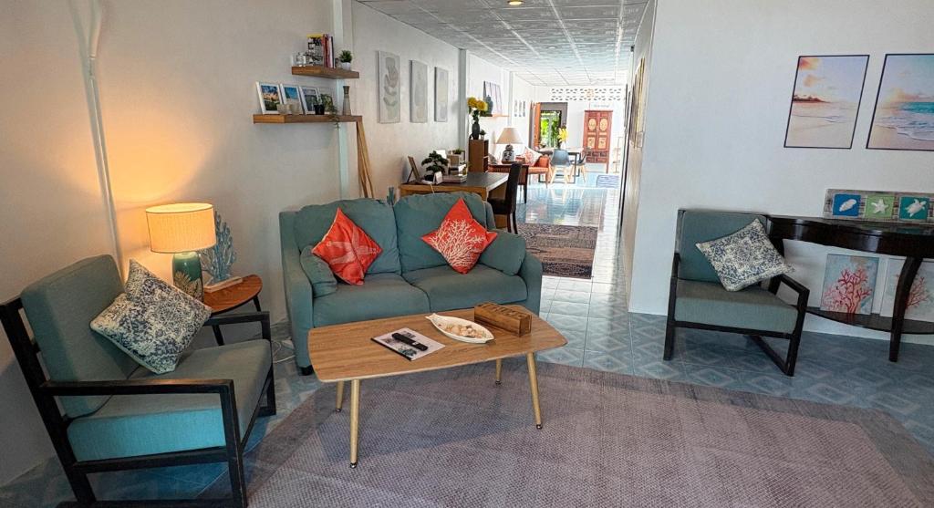 un salon avec un canapé, des chaises et une table dans l'établissement Coral Cottage Beach House @ Phang Nga, à Thai Muang