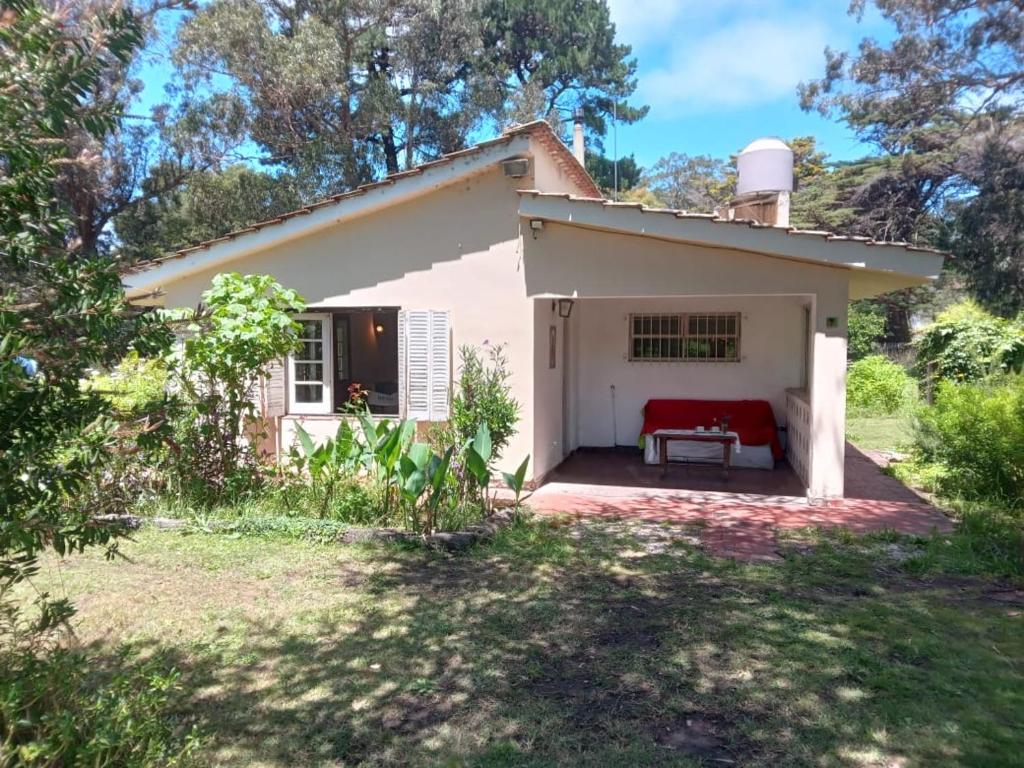 a small white house with a red couch in a yard at Casa Acantilados Chapadmalal in Colonia Chapadmalal