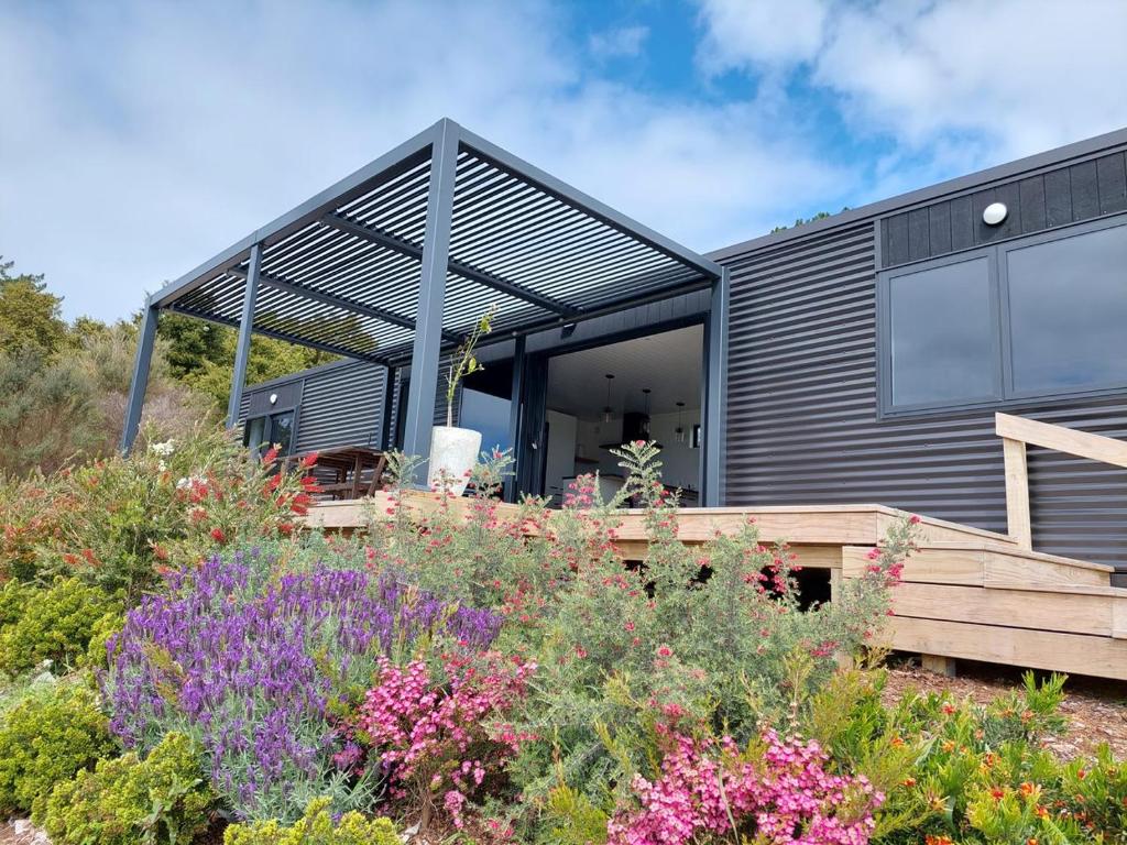 a black house with a deck and some flowers at Onewhero Country Cabin in Onewhero