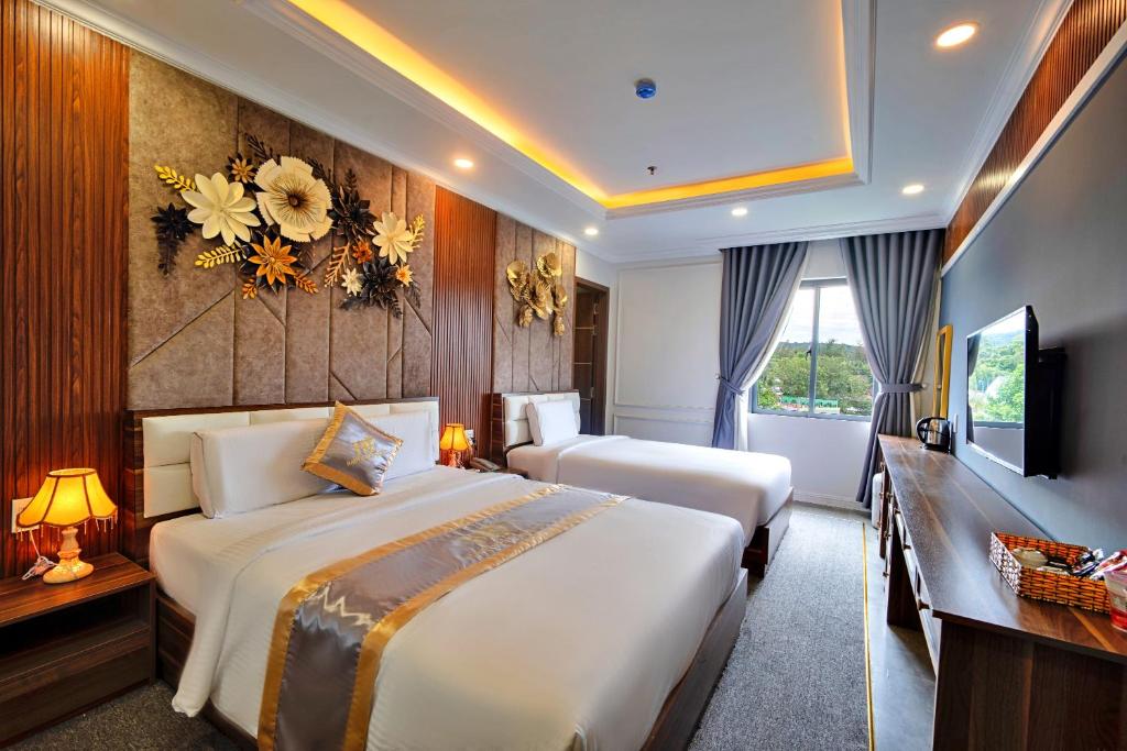 una camera d'albergo con due letti e una televisione di S79 Happy Hotel Phu Quoc a Phu Quoc