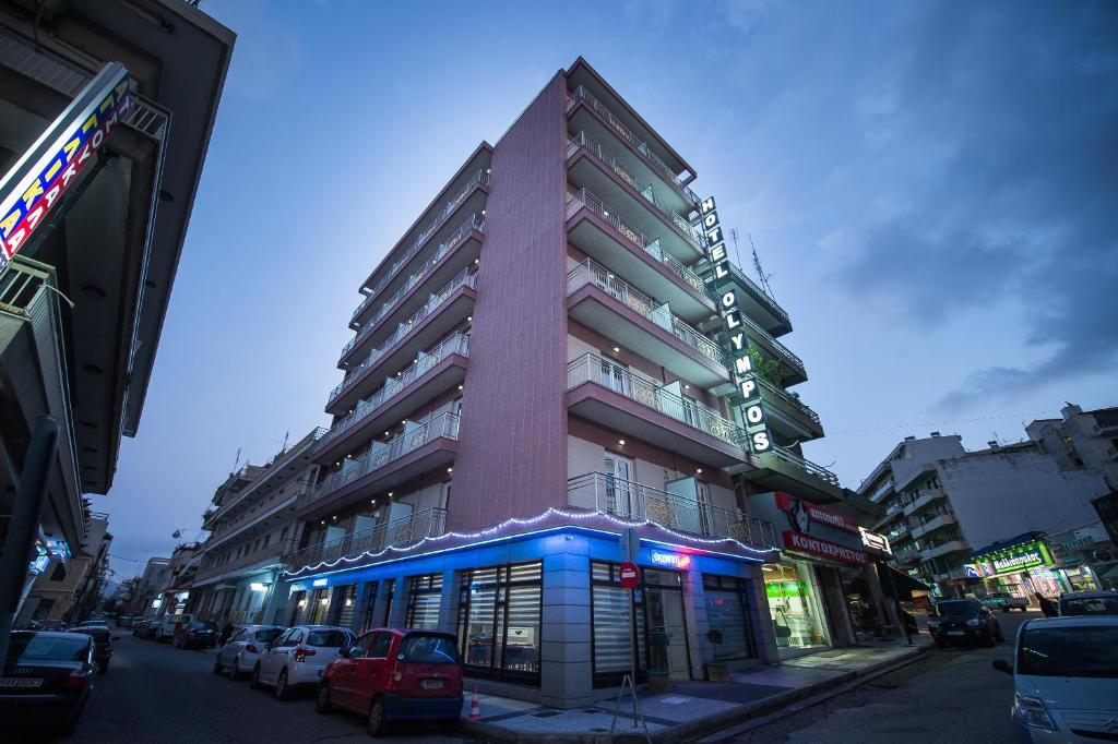 un edificio alto en una calle de la ciudad con coches aparcados en Hotel Olympos, en Pyrgos