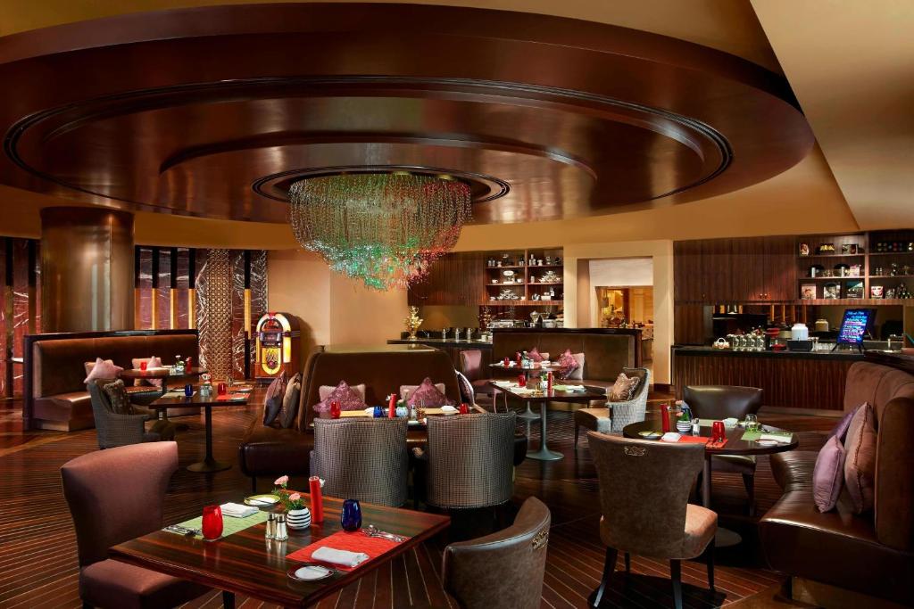 a restaurant with tables and chairs and a chandelier at ITC Grand Chola, a Luxury Collection Hotel, Chennai in Chennai