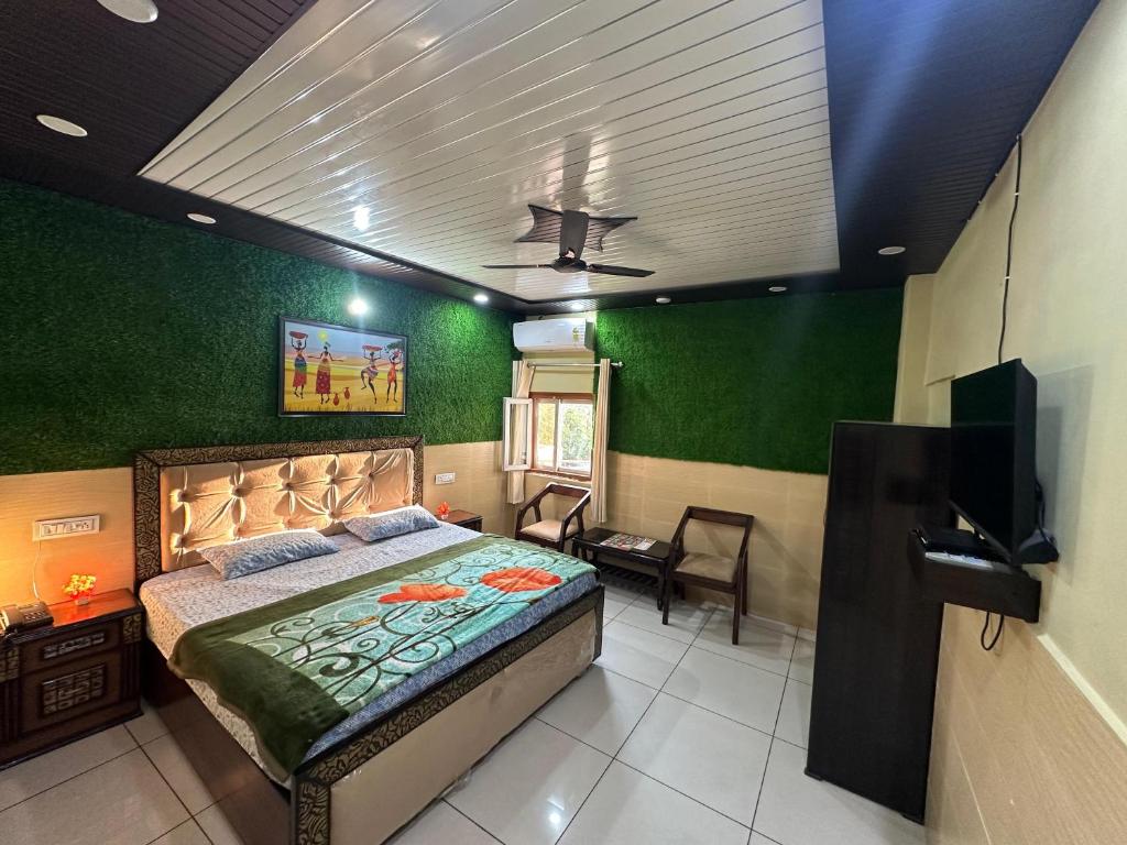a bedroom with a bed with green walls and a ceiling at Sadyal Hotel And Restaurant in Tīra Sujānpur