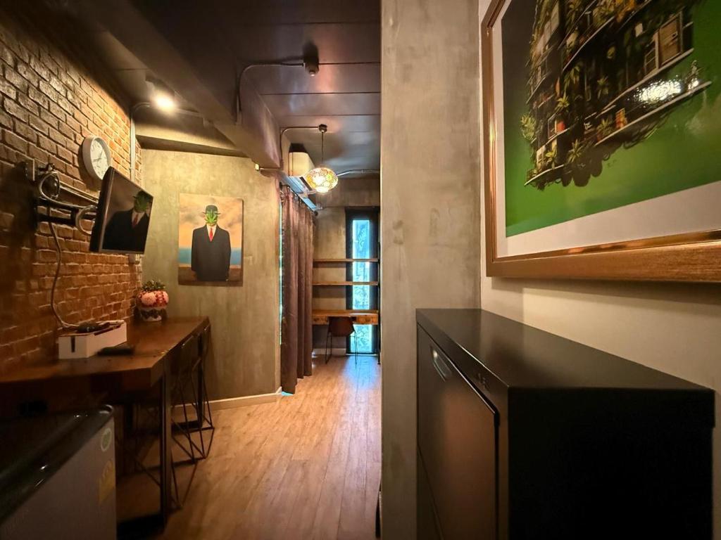 A compact living area with a desk, television, mini-fridge and industrial artwork.