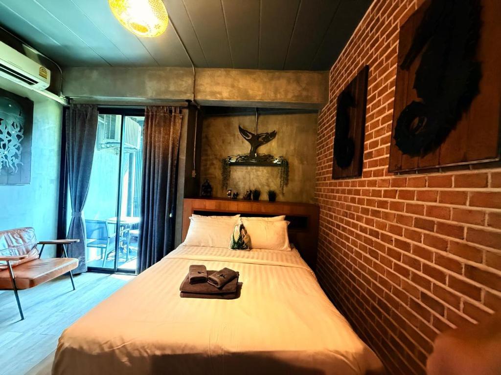 A bedroom with a double bed, exposed brick wall, seating area and glazed balcony or window opening.