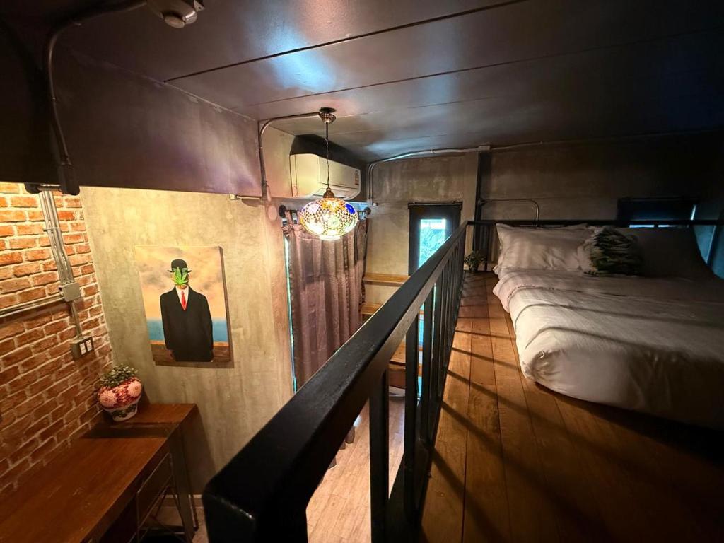 A loft-style sleeping area reached beside a black railing, with a bed on an elevated level.