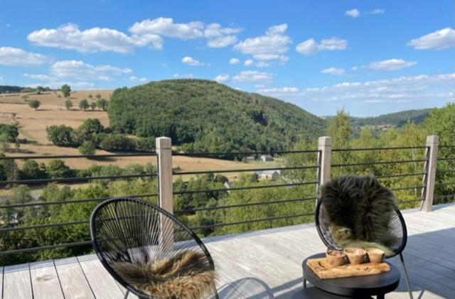 a cat sitting on top of a porch with two chairs at Suites de la vallee 2 in Érezée