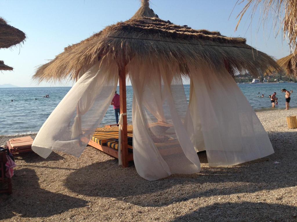 Una cama bajo una sombrilla de paja en una playa en Beachfront Apartment, en Orikum