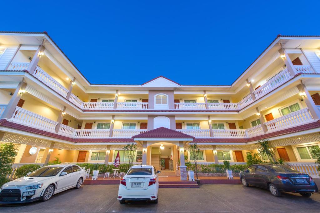 two cars parked in front of a large building at Nuntiya Terrace in Udon Thani