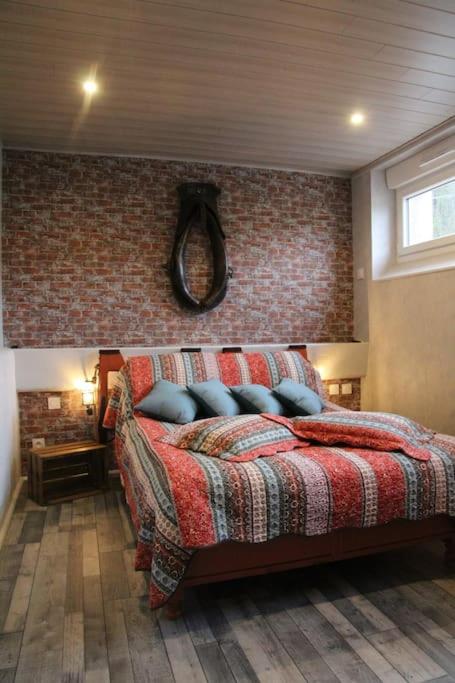 une chambre avec un lit avec un mur de briques dans l'établissement L'Etablourotte, ancienne étable, à Herpelmont