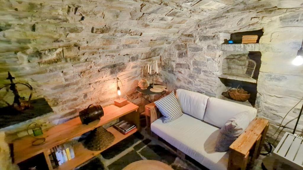 - un salon avec un canapé blanc et un mur en pierre dans l'établissement La Ca' nel Borgo, à Moltrasio