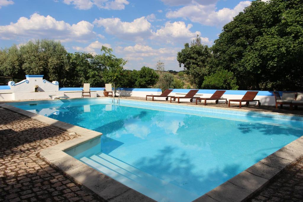 a large swimming pool with chairs and blue water at Tapada da Rabela - Reserva Natural in Marvão