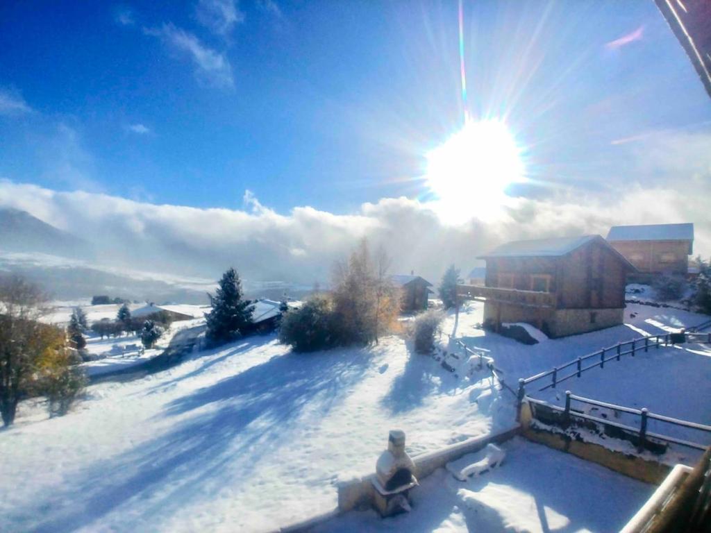 une personne assise dans la neige avec le soleil dans le ciel dans l'établissement Superbe T3 esprit chalet avec vue panoramique, à Font-Romeu