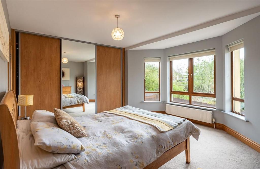 um quarto com uma cama grande e 2 janelas em Kenmare HH em Kenmare