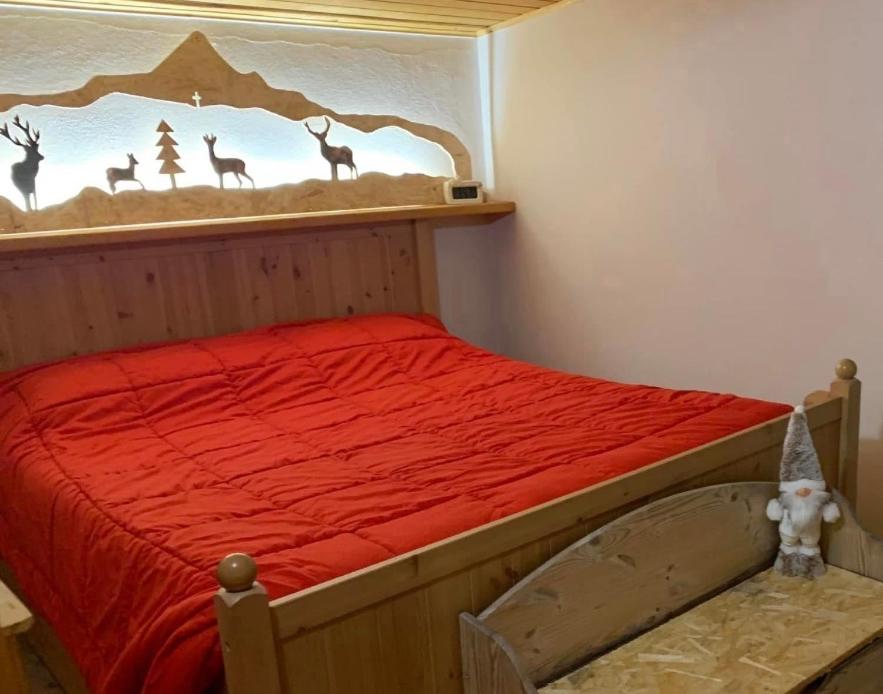 ein Schlafzimmer mit einem Bett mit roter Bettwäsche und einem Hirsch-Wandbild in der Unterkunft DOSSENA Splendido Chalet di Montagna immerso nella natura in Madonna della Costa
