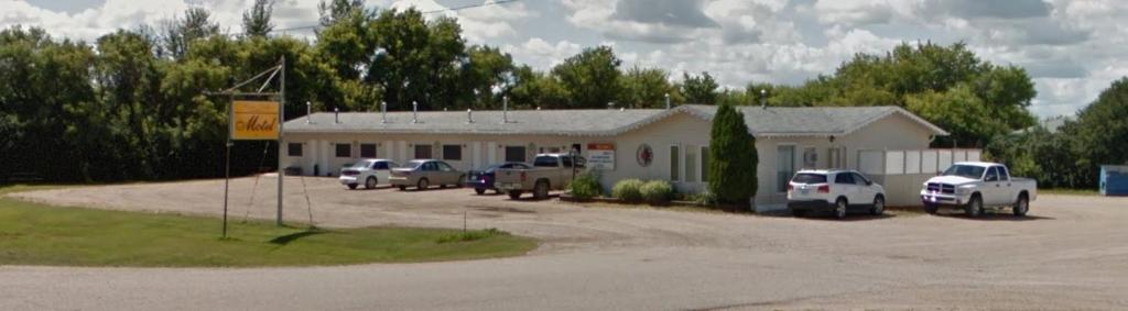 a parking lot with cars parked in front of a building at Wakaw Lodge Motel in Wakaw