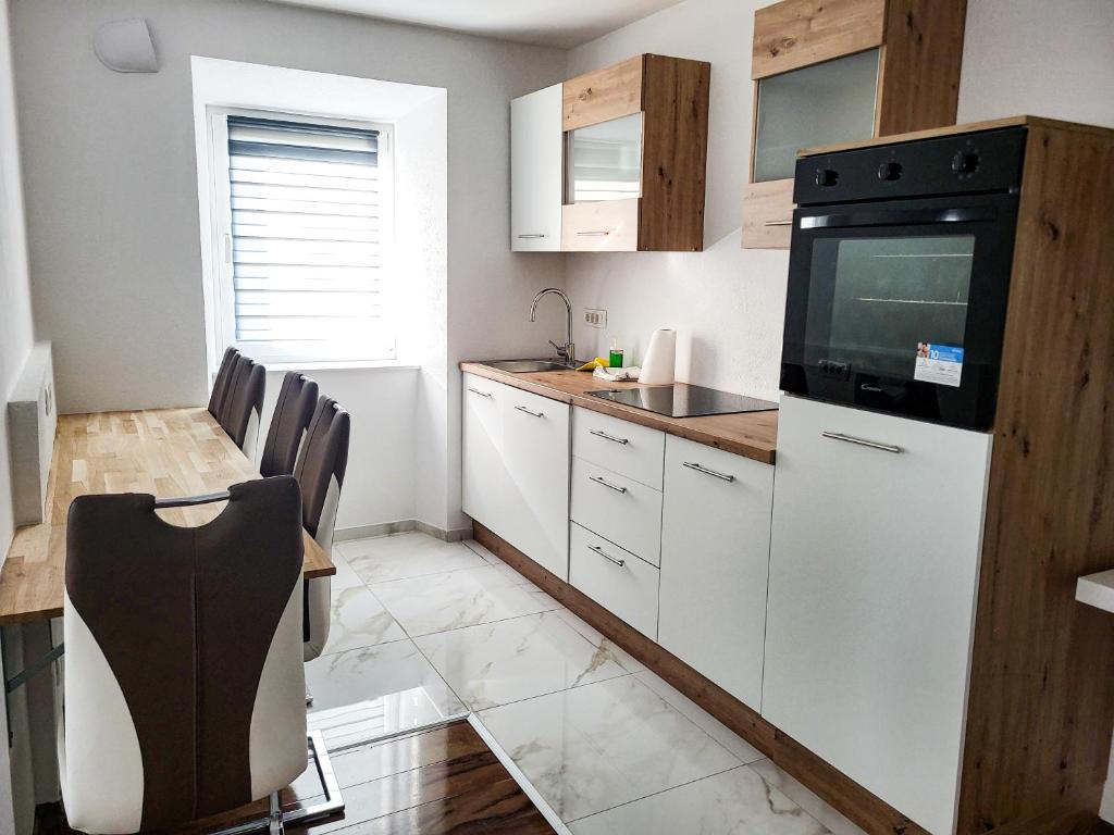 a kitchen with white cabinets and a black appliance at Stara Pošta Apartment 7 in Grosuplje