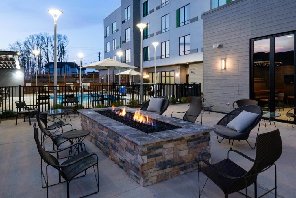 a patio with chairs and a fire pit in front of a building at Courtyard Charlotte Steele Creek in Charlotte