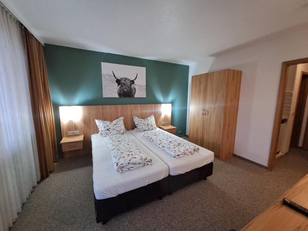 a bedroom with a bed with a picture of a cow on the wall at Chiemgau Appartement Lärche 3 Chiemgau Karte inklusive in Inzell