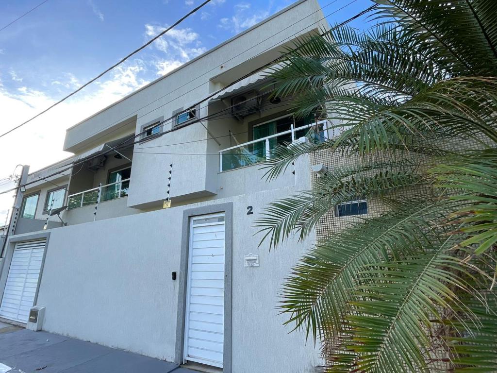 a white building with a door and a palm tree at Casa em Vilas 70m da Praia in Lauro de Freitas