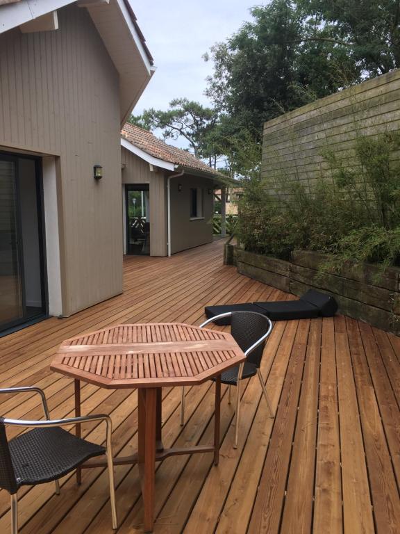 une terrasse en bois avec une table et des chaises. dans l'établissement Villa LACANAULAISE, à Lacanau