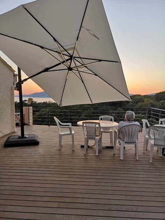 un homme assis à une table sous un parasol sur une terrasse dans l'établissement Vue Panoramique, à Porticcio