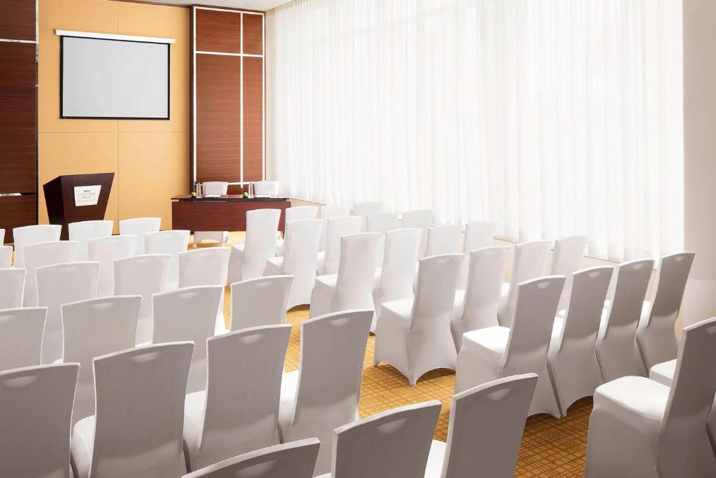 a conference room with white chairs and a screen at Courtyard by Marriott Kochi Airport in Nedumbassery