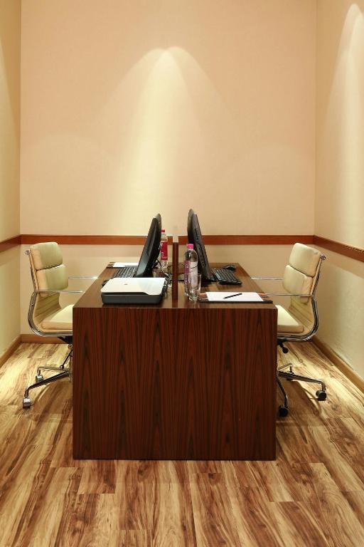 an office with two computers on a desk with two chairs at Courtyard by Marriott Kochi Airport in Nedumbassery
