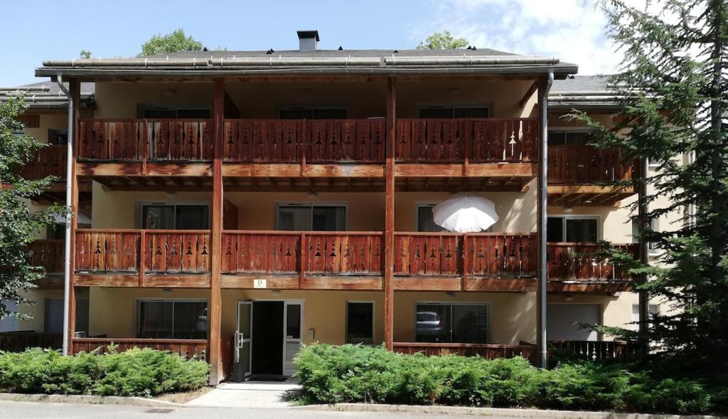 un immeuble d'appartements avec balcon et arbres dans l'établissement Résidence DOMAINE DE LA VALEE D'AX, à Ax-les-Thermes