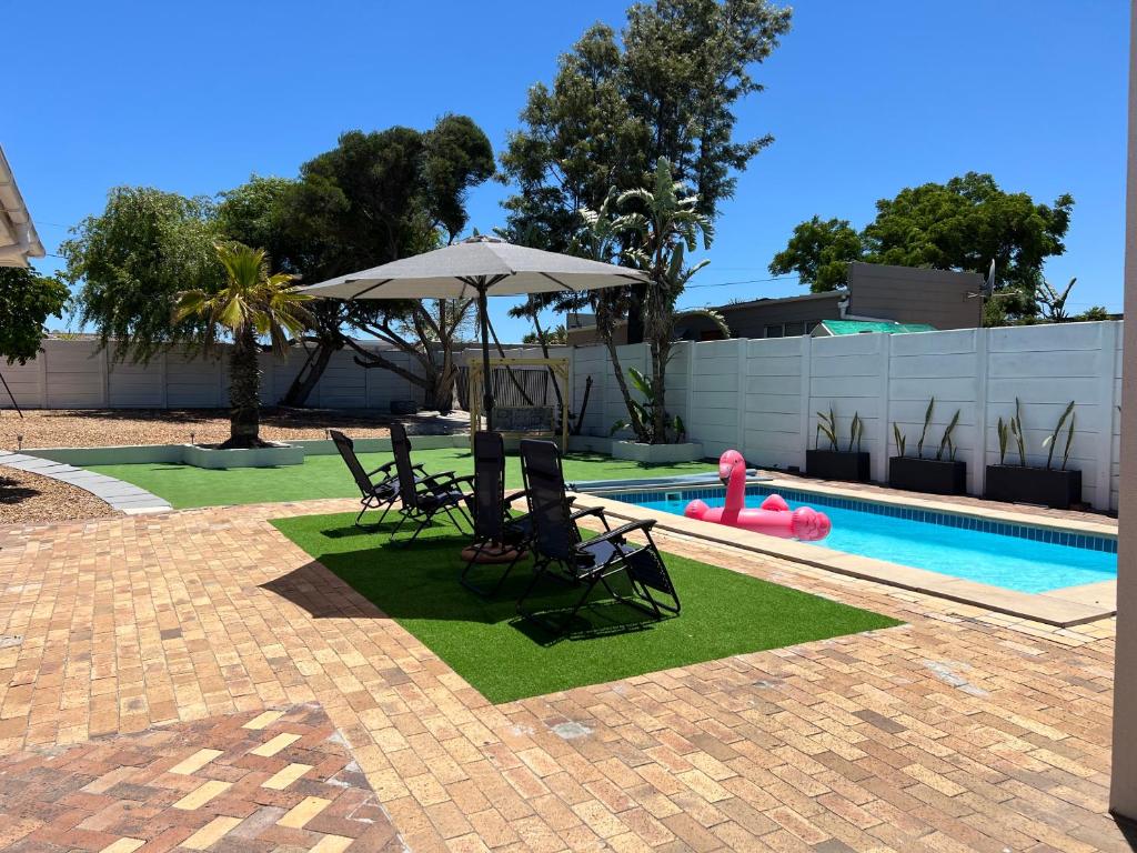 een zwembad met stoelen en een parasol naast een zwembad bij Villa Lamsyh- your second home in Kaapstad