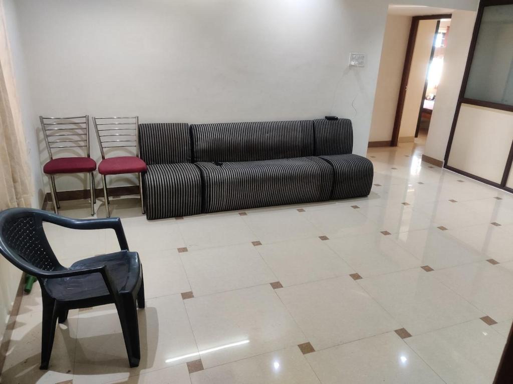 a living room with a black couch and a chair at Place away from home in Hyderabad