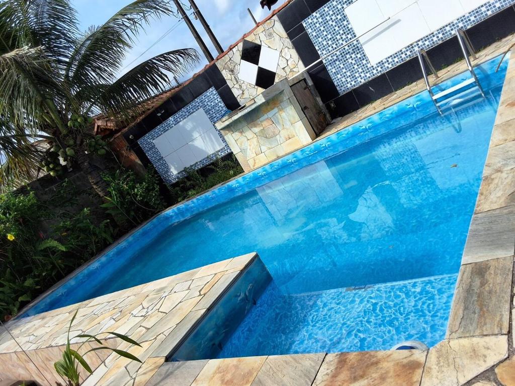 a large blue swimming pool in front of a house at Casa com pisicna in Mongaguá in Mongaguá