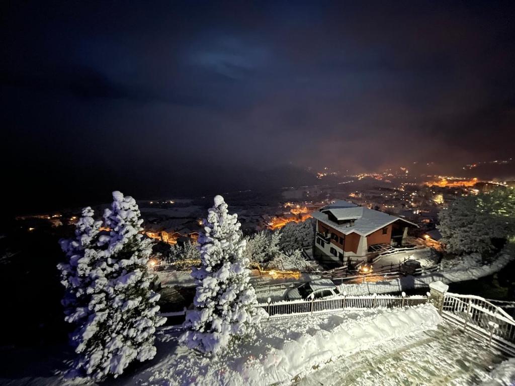 a building with snow covered trees at night at Riflessi Alpini in Saint Vincent