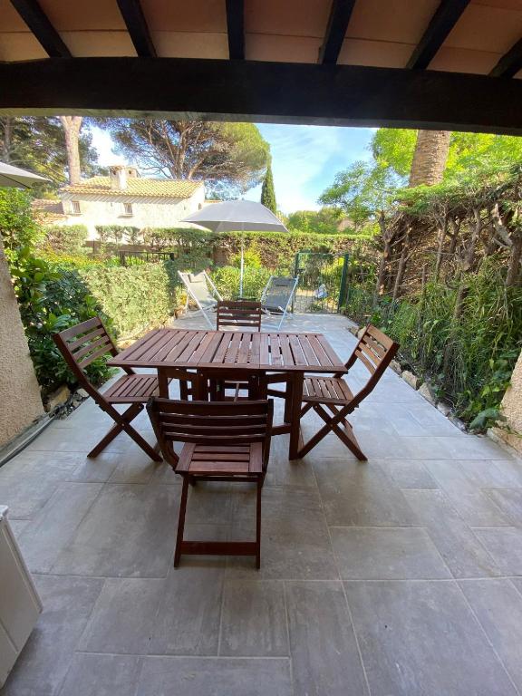 - une table en bois avec des chaises et un parasol sur la terrasse dans l'établissement Les jardins de la mer - Calme - Terrasse - Parking - 200m de la mer, aux Lecques